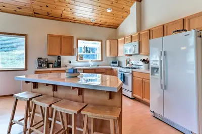 a kitchen with a white refrigerator and wooden cabinets at Forest Views and Beach Access Family Truckee Gem in Truckee
