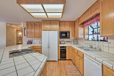 a kitchen with wooden cabinets and a white refrigerator at Near Bear Valley Peaceful Arnold Home with Hot Tub in Arnold