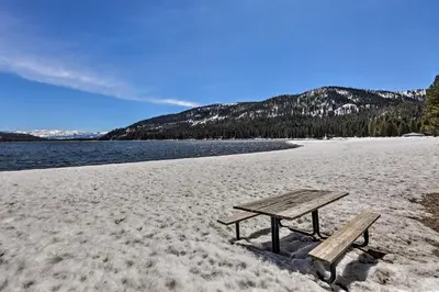 a picnic table sitting on a beach next to the water at 5 Mi to Skiing! Family Getaway Near Donner Lake in Truckee