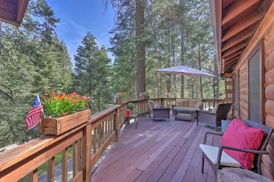 a wooden deck with chairs and an umbrella on a cabin at 11 Mi to Apple Hill Pollock Pines Resort Cabin in Pollock Pines