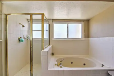 a bathroom with a tub and a shower with a window at Waterfront Discovery Bay Home Outdoor Bar and Dock in Discovery Bay