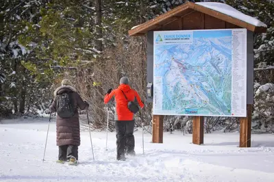 two people standing next to a sign in the snow at Spike's Place in Truckee