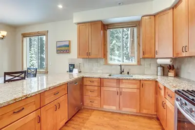 a kitchen with wooden cabinets and wooden floors and windows at 4 Mi to Skiing Truckee Escape with Deck in Truckee
