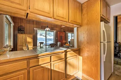a kitchen with wooden cabinets and a refrigerator at Near Hiking and Skiing Bear Valley Cabin! in Tamarack