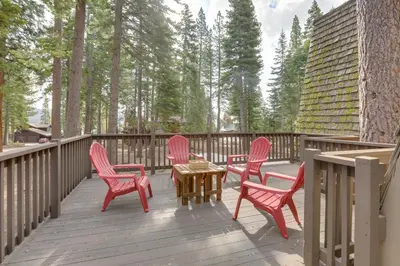 four chairs and a table on a deck with trees at Near Skiing and Hiking Carnelian Bay Cabin in Carnelian Bay