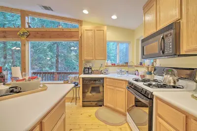 a kitchen with wooden cabinets and a stove top oven at Walk to Big Trees State Park Cabin with Deck! in Dorrington