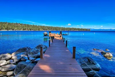 a dock on a lake with a boat in the water at Hot Tub and Lake Tahoe Views Waterfront Retreat in Tahoma