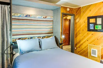 a bed in a room with a wooden wall at Sequoia Forest Remote Retreat! Dreamtime Cabin in Ponderosa