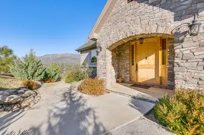 a stone house with a wooden door and a driveway at 28 Mi to Yosemite Lovely Mtn Cottage with Deck! in North Fork