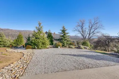a driveway with a stone wall and trees at 28 Mi to Yosemite Lovely Mtn Cottage with Deck! in North Fork