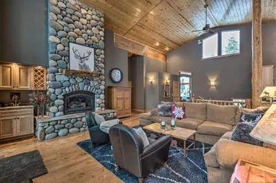 a living room with a stone fireplace and a couch at Tahoe Donner Mountain Cabin Surrounded by Forest! in Truckee