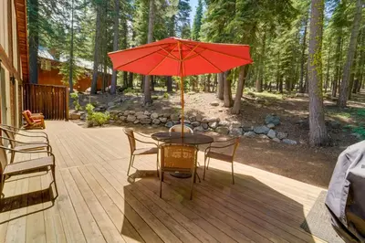 a table with a red umbrella on a deck at Tahoe Donner Mountain Cabin Surrounded by Forest! in Truckee