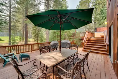 a table with a green umbrella on a deck at Truckee Home with Private Hot Tub on a Golf Course in Truckee