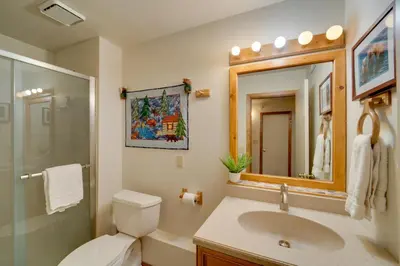 a bathroom with a toilet and a sink and a mirror at Truckee Home with Private Hot Tub on a Golf Course in Truckee