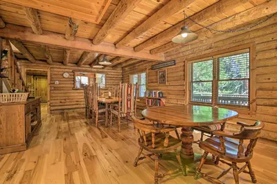 a dining room with a table and chairs in a log cabin at 5 Mi to Hiking Custom Cabin with Deck in Arnold! in Arnold
