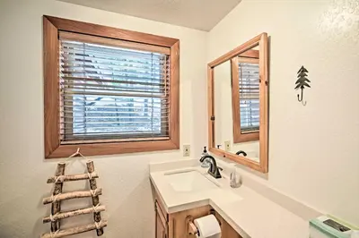 a bathroom with a sink and a mirror and a window at 5 Mi to Hiking Custom Cabin with Deck in Arnold! in Arnold