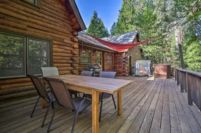 a wooden deck with a table and chairs on a cabin at 5 Mi to Hiking Custom Cabin with Deck in Arnold! in Arnold