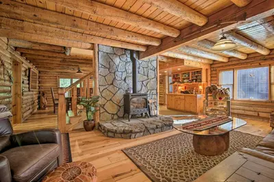 a living room with a fireplace in a log cabin at 5 Mi to Hiking Custom Cabin with Deck in Arnold! in Arnold