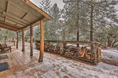 a covered porch with a pile of fire wood at Creekside Cabin 8 Mi to Kings Canyon National Park in Miramonte