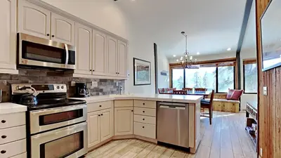 a kitchen with white cabinets and a dining room at Spectacular 3 Bedroom Townhome with Pool in Mammoth Lakes