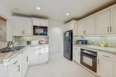 a kitchen with white cabinets and a black refrigerator at Skyline Serenity in South Lake Tahoe