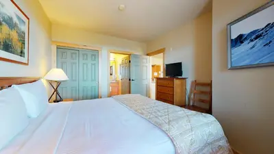 a bedroom with a large white bed and a television at Sunstone #209 condo in Mammoth Lakes