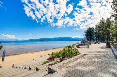 a beach with people sitting on a bench next to the water at Country Club Retreat in South Lake Tahoe