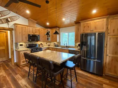 a kitchen with a large kitchen island with a stainless steel refrigerator at Pioneer in Oakhurst