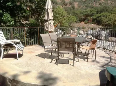 a patio with a table and chairs and an umbrella at The Gateway Restaurant & Lodge in Three Rivers