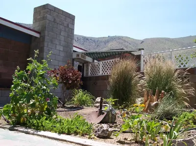 a garden in front of a house with mountains in the background at Toiyabe Motel in Walker