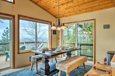 a dining room with a table and chairs and windows at Near Hiking Home with Deck in Twain Harte! in Twain Harte