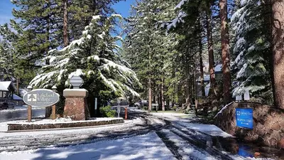 a snow covered street with a sign and trees at Lakeland Village #105 in South Lake Tahoe