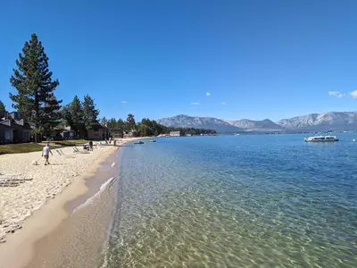 a beach with people sitting on the sand and water at Lakeland Village #110 in South Lake Tahoe