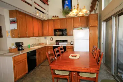 a kitchen with a wooden table and a white refrigerator at SIerra Park Villas #06 in Mammoth Lakes