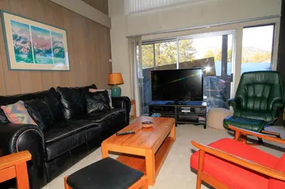 a living room with a black leather couch and a tv at Sierra Park Villas 24 in Mammoth Lakes