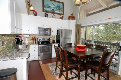 a kitchen with a wooden table and chairs and a kitchen with a sink at Sierra Park Villas 03 in Mammoth Lakes