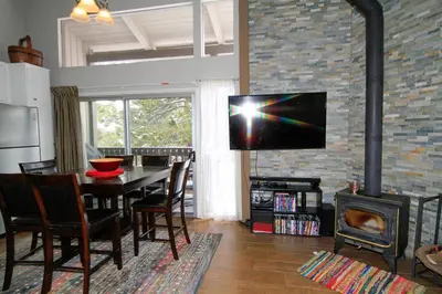 a living room with a table and a television on a brick wall at Sierra Park Villas 03 in Mammoth Lakes