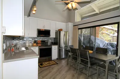 a kitchen with white cabinets and a table with chairs at Sierra Park Villas 93 in Mammoth Lakes