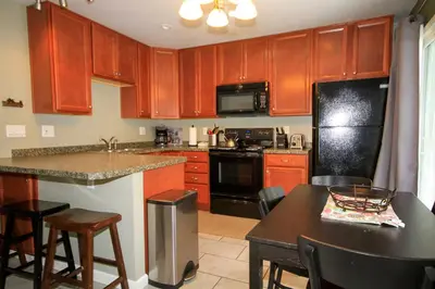 a kitchen with wooden cabinets and a black refrigerator at Sierra Park Villas 65 in Mammoth Lakes