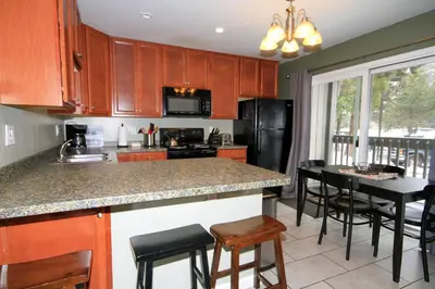 a kitchen with wooden cabinets and a island with bar stools at Sierra Park Villas 65 in Mammoth Lakes