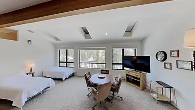 a bedroom with two beds and a table and a tv at Comfortable 2 BR Loft Slope View Condo! in Mammoth Lakes