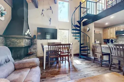 a living room with a staircase and a table and chairs at North Lake Loft in Kings Beach