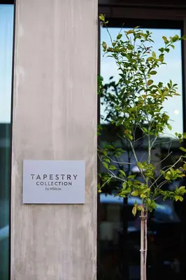 a sign on the side of a building with a tree at Tapestry By Hilton The Fort Sutter Hotel Sacramento, Ca in Sacramento