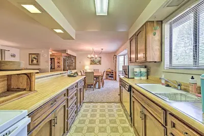 a large kitchen with wooden cabinets and a dining room at Home with Serene Deck in Twain Harte! in Twain Harte