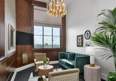 a living room with a green couch and a chandelier at The Darling in Visalia