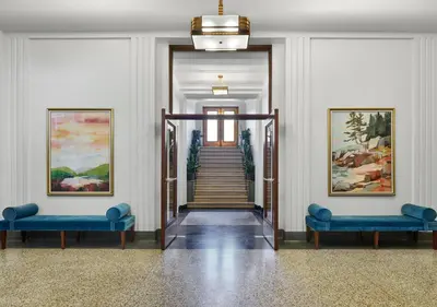 a hallway with two blue chairs and a staircase at The Darling in Visalia