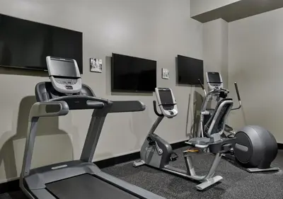 a gym with three exercise bikes and three televisions at The Darling in Visalia