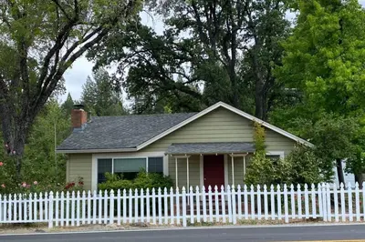 a small white house with a white picket fence at Vans Yosemite Garden Cottage in Groveland