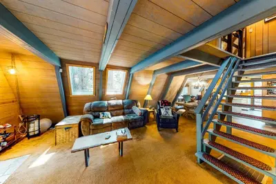 a living room with a staircase in a house at Under The Trees in Camp Connell