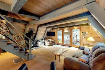 a living room with a staircase in a cabin at Under The Trees in Camp Connell
